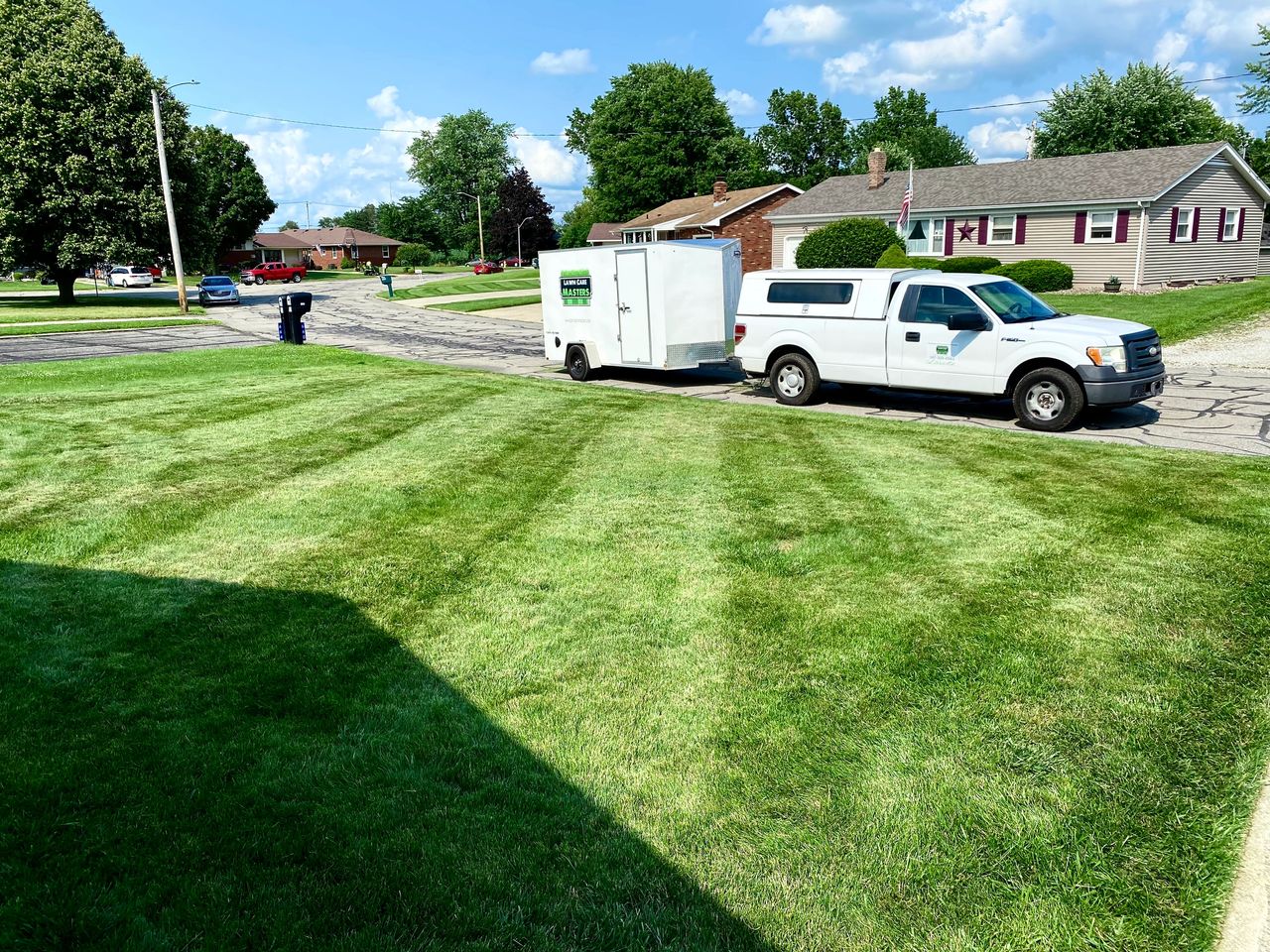 Lawn Care Masters truck and trailer beside a freshly mowed lawn